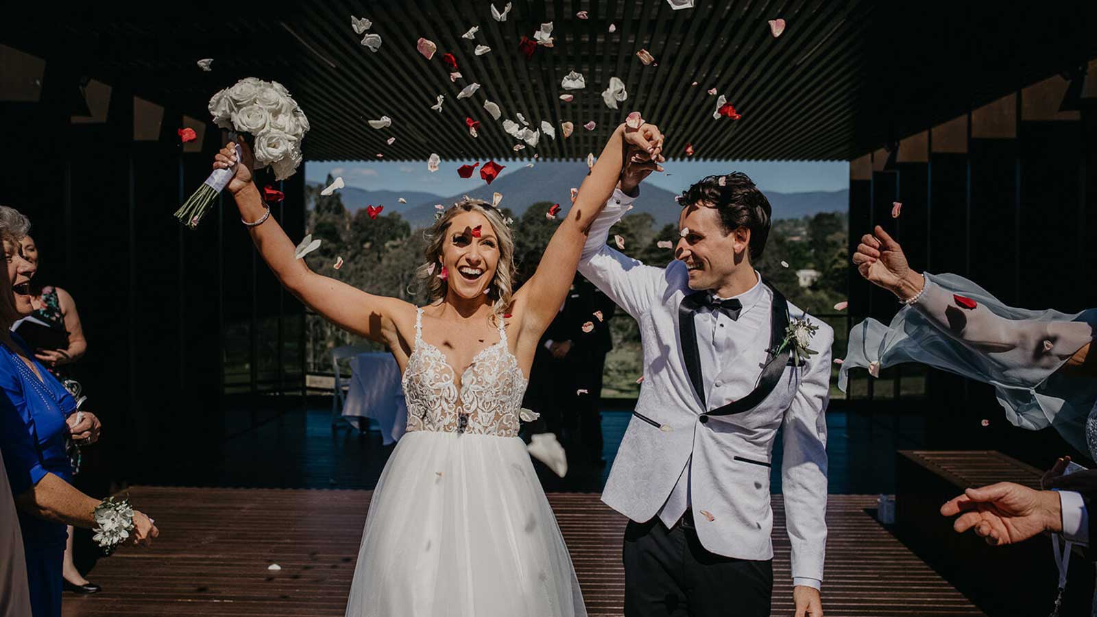 Bride and groom celebrating amongst rose petals, after getting married at Healesville.