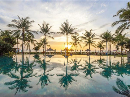 Sunset in Bali by a resort surrounded with palm trees. 