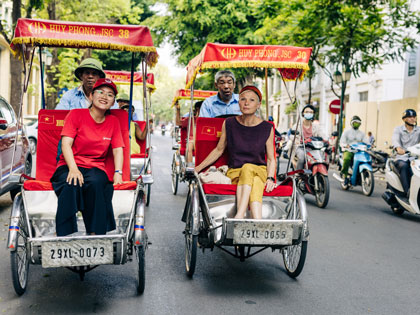 Tourist and tour guide sitting on small cars in Hanoi