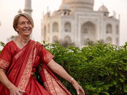 A woman dressed in traditional clothing with a temple behind her. 