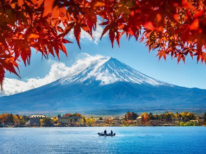Mount Fuji with a lake and bright orange leaves in the foreground