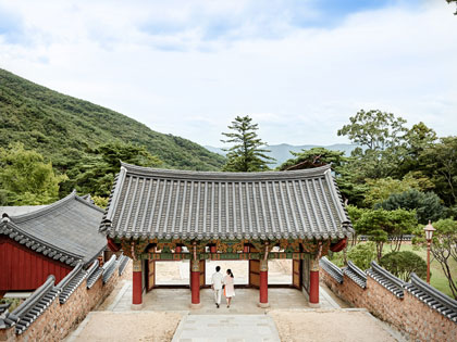 Couple walking under a japanese structure with natural views. 