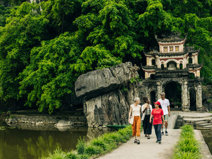 Small tour group walking by a temple entrance in Vietnam.