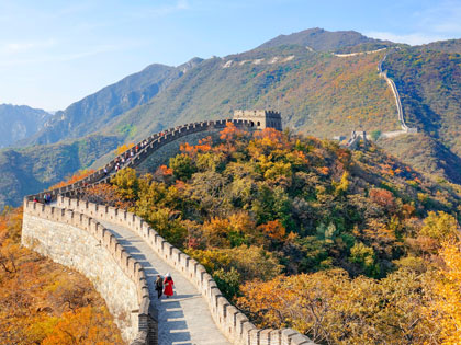 Two tourists walk along the walkway atop the Great Wall of China.