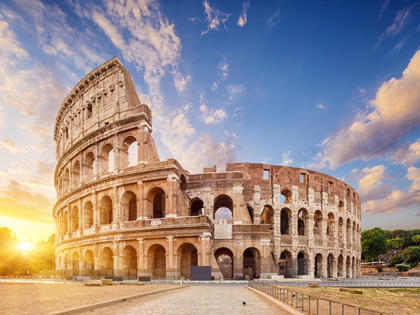 Coliseum with blue skies and the sun setting in Rome, Italy.