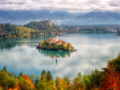Small island surrounded by water with autumn trees
