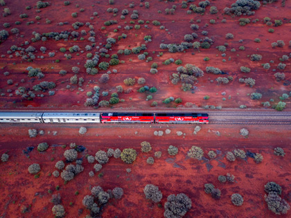 The Ghan going through the outback surrounded by red sand