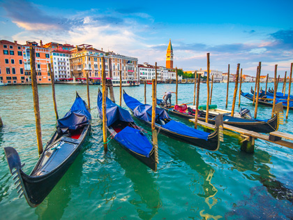 Several small boats lined up in the Venice Grand Canal.