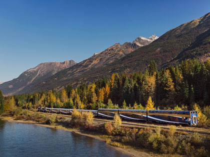 The Rocky Mountaineer train coasting along some water with beautiful views.