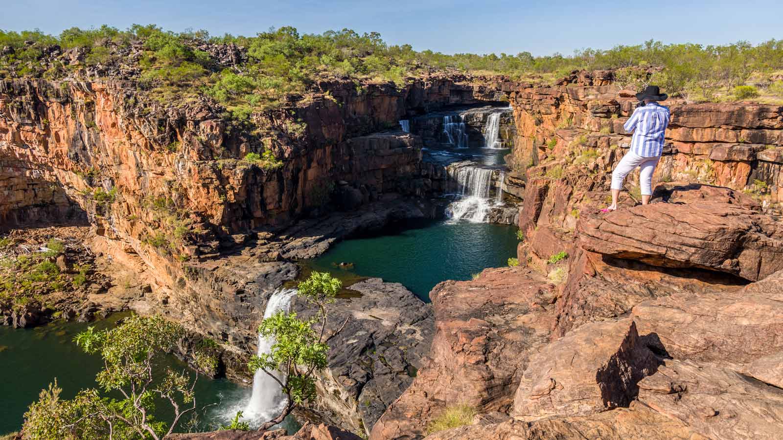 Woman standing on a rock to look at a waterfall