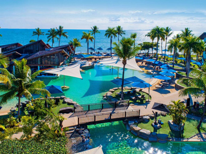 Aerial view of a luxury resort in Fiji with bright blue pools and palm trees.