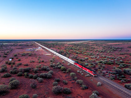 The Ghan train at dusk passing by a very small township.