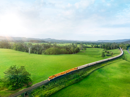 A long train travelling through some green fields in NSW, Australia.