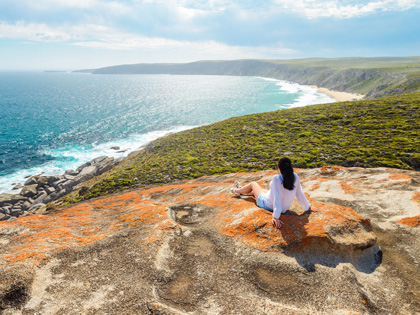 Woman enjoying the scenery while sitting on the edge of a cliff 