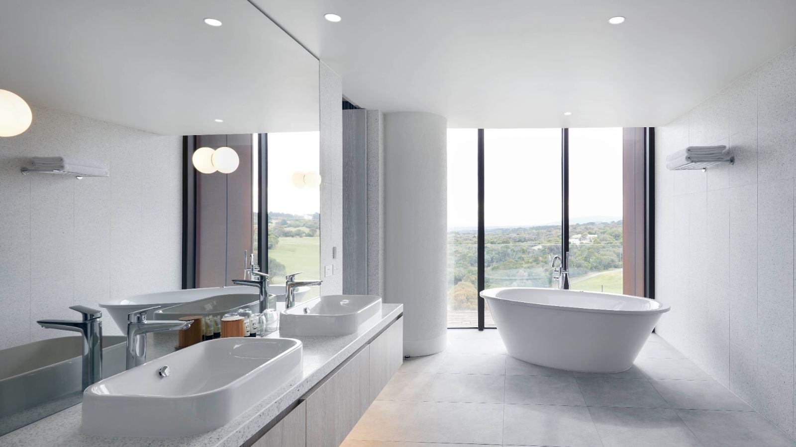 A view looking out from the inside of a luxurious bathroom over the modern roll top bath to Cape Schanck's scenic outdoors