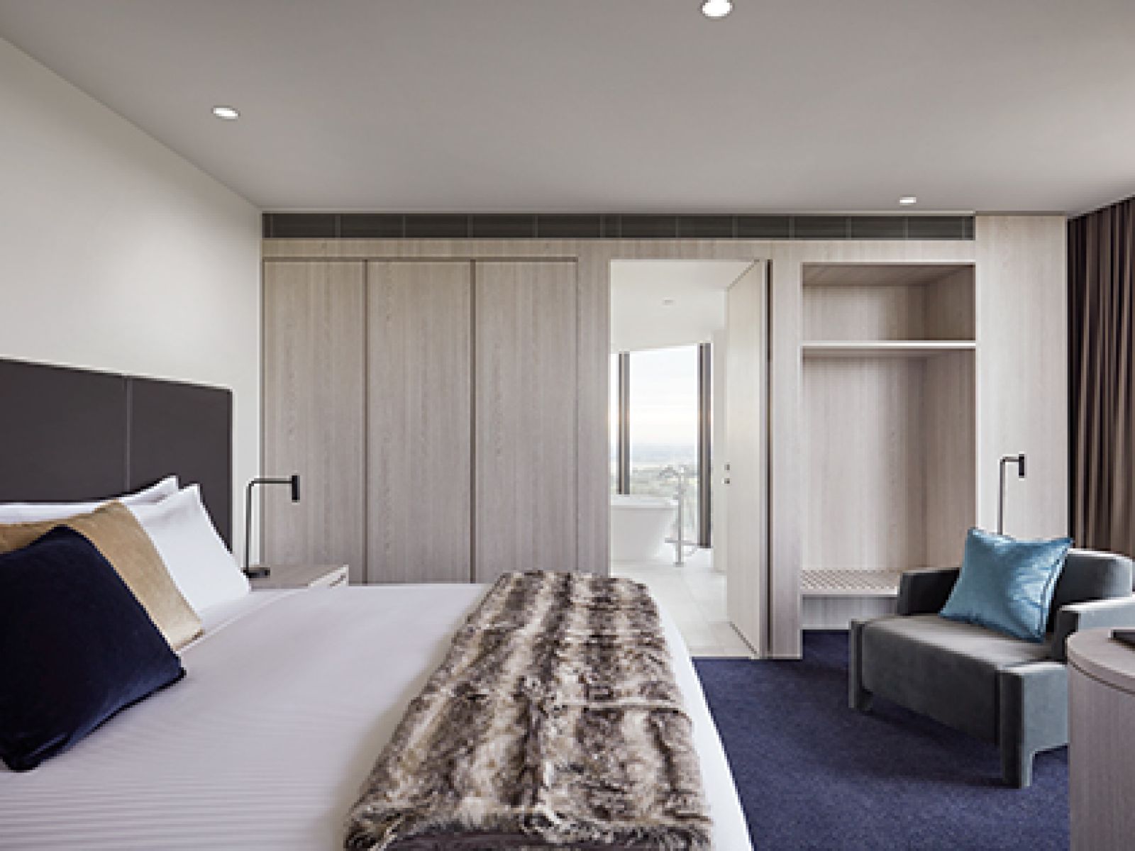 Bedroom in Deluxe Spa Family Suite at RACV Cape Schanck Resort, featuring a large bed, couch and television, and leading to a spa ensuite.