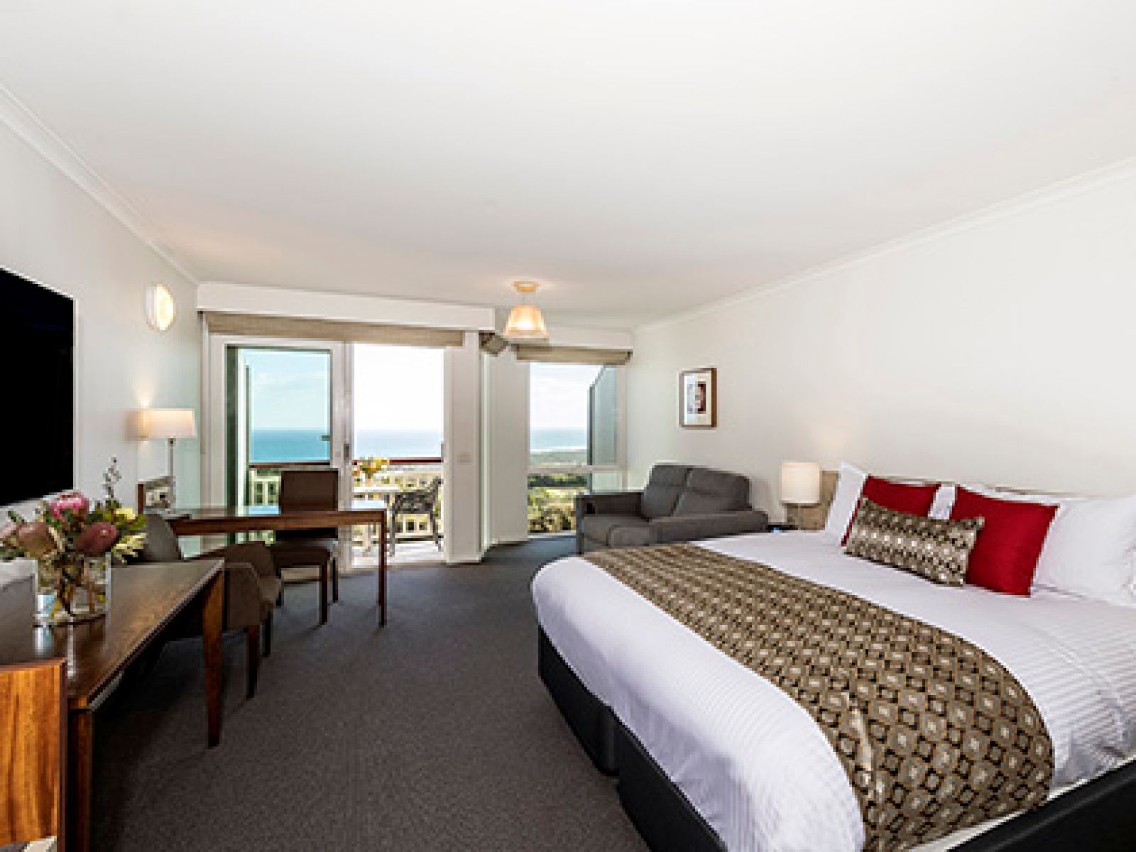 The Ocean View room at RACV Cape Schanck Resort, featuring a king bed, a floral arrangement, a dining table, and a private balcony.
