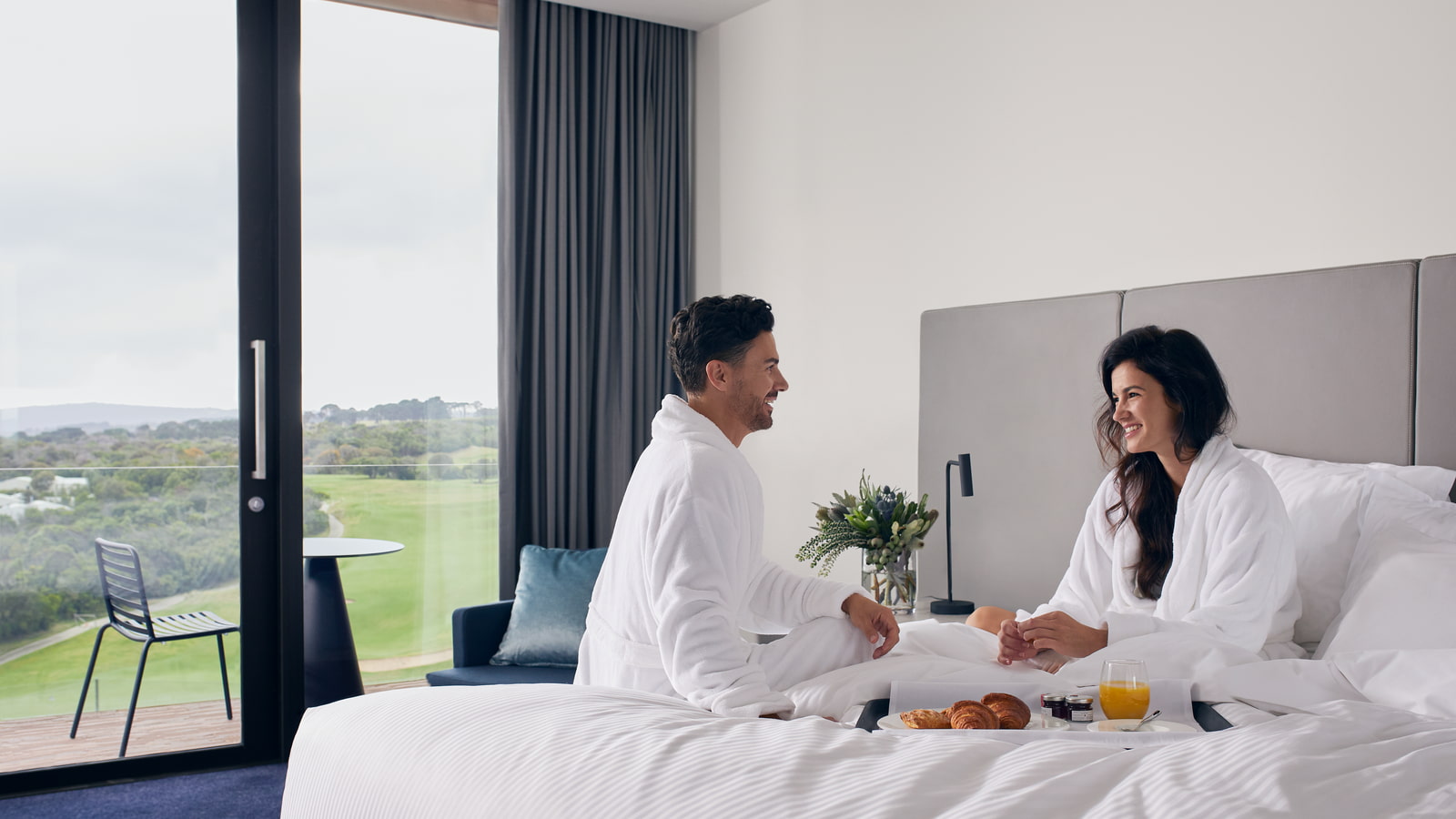 Couple eating breakfast on a bed in RACV's Cape resort room.