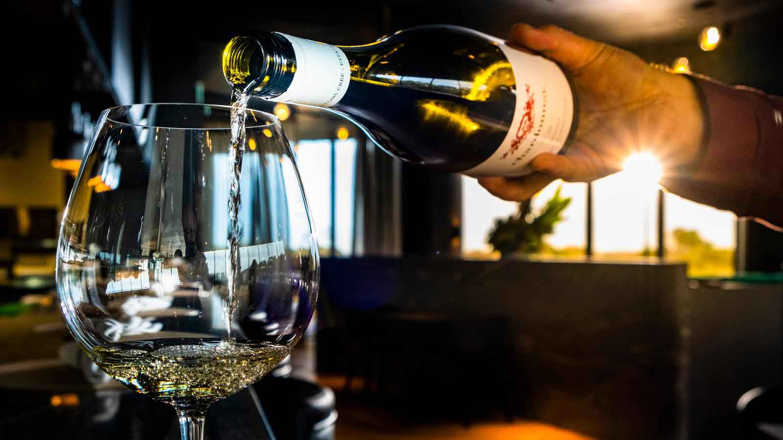 A tight shot of a glass of wine being poured by a waiter at Cape restaurant.
