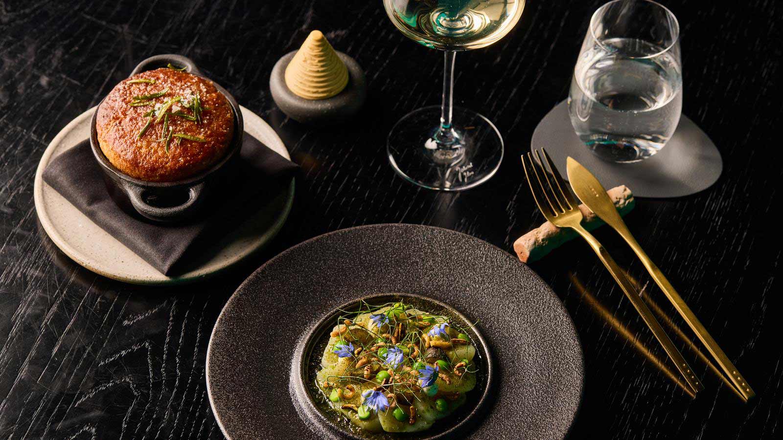 Several dishes presented beautifully alongside wine and cutlery.