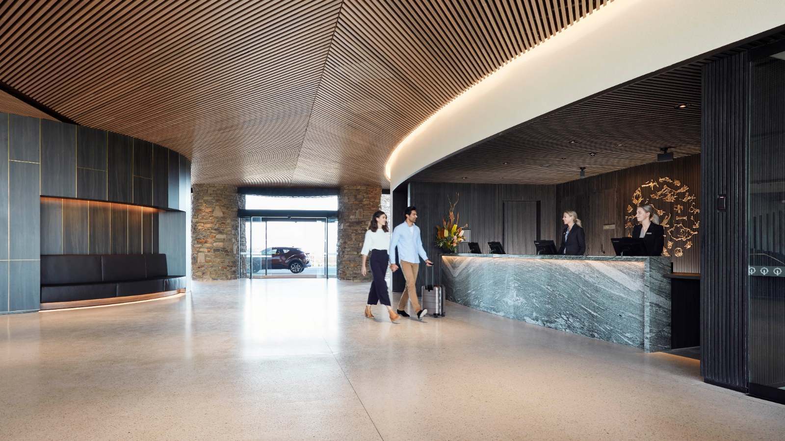 A couple walk up to reception in the stunningly architected lobby of RACV Cape Schanck Resort