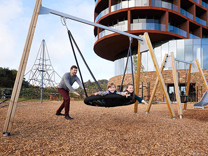 Person pushing two children on a playground swing at RACV Cape Schanck Resort.