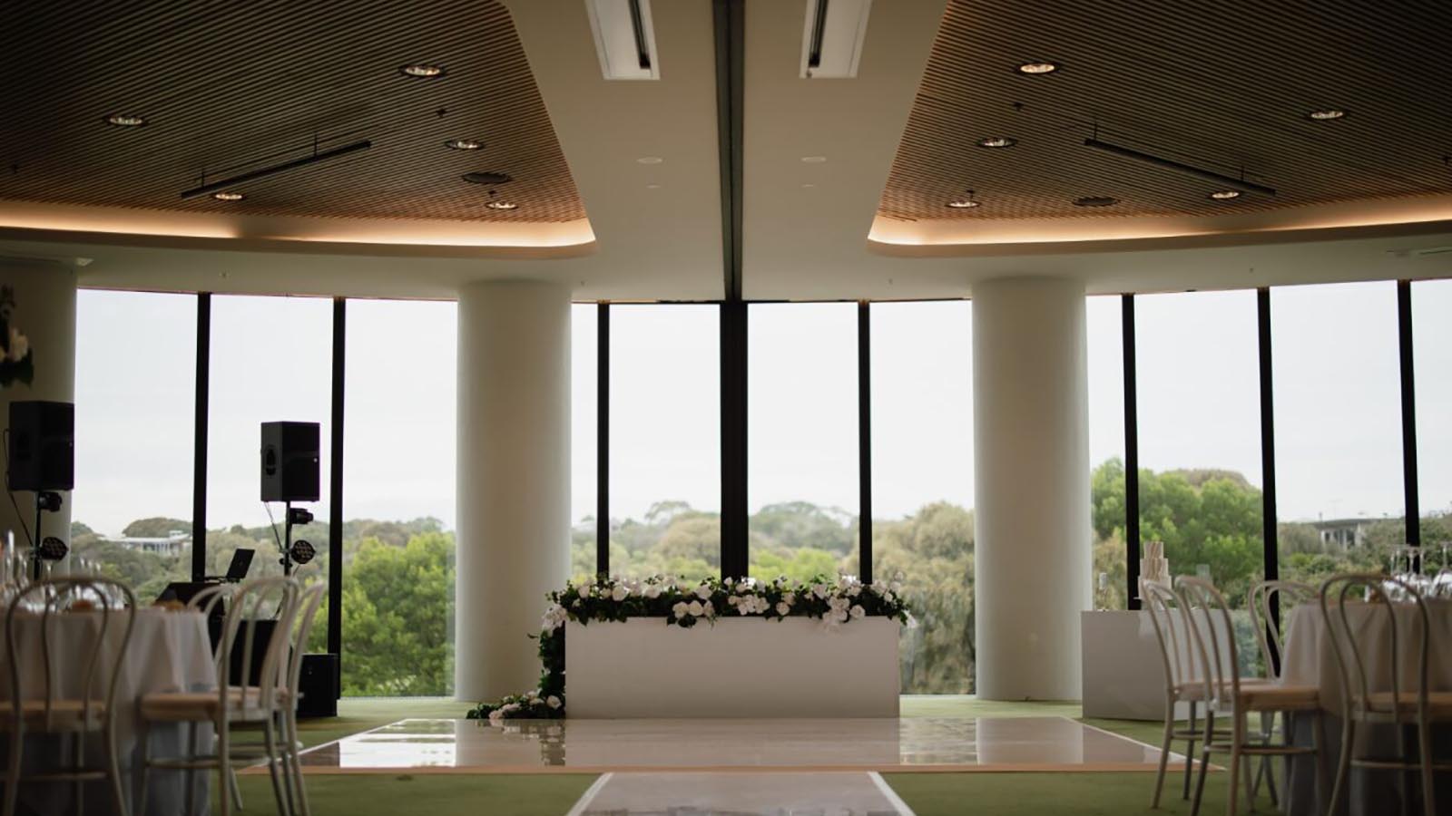 Room at RACV Cape Schanck resort set up for wedding reception, with dance floor and white flowers.