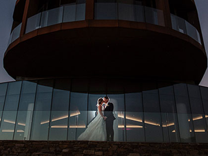 Bride and groom kissing on balcony at RACV Cape Schanck Resort at dusk.
