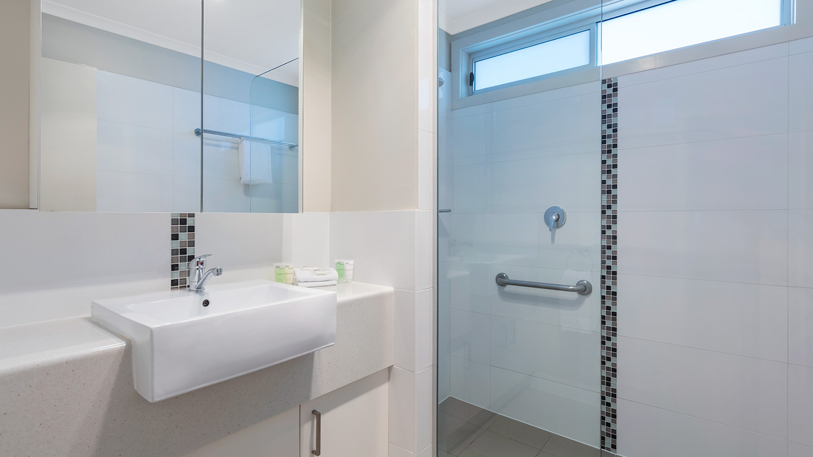 Bathroom in RACV Cobram Resort's Lakeview Cabin, featuring a large mirror, sink and shower, and complimentary toiletries.