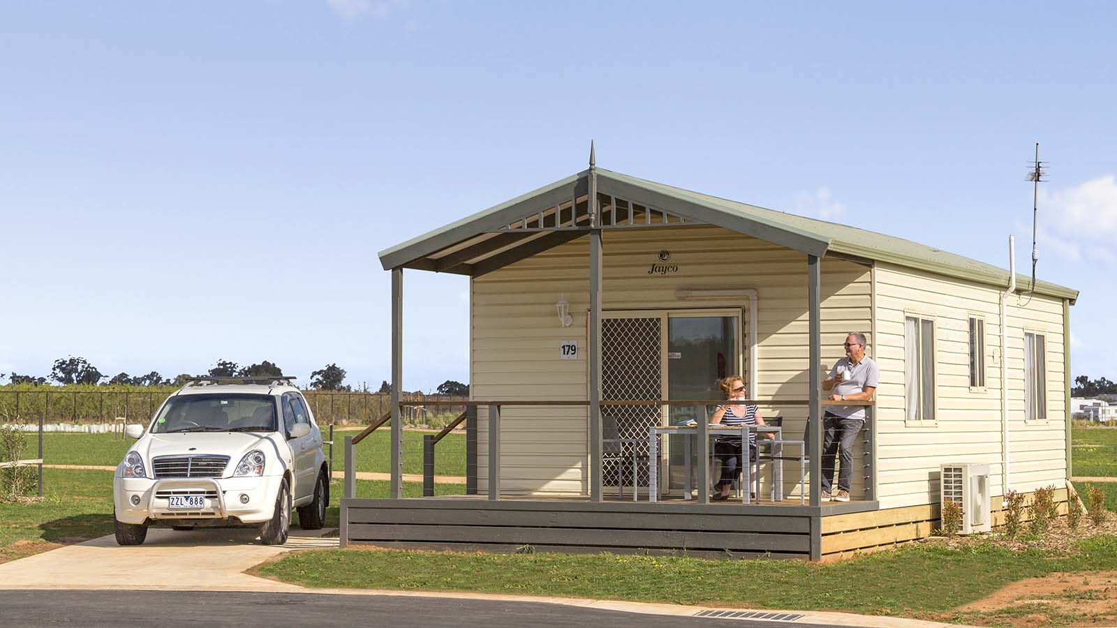 Two people chatting on porch of a park cabin at RACV Cobram Resort.