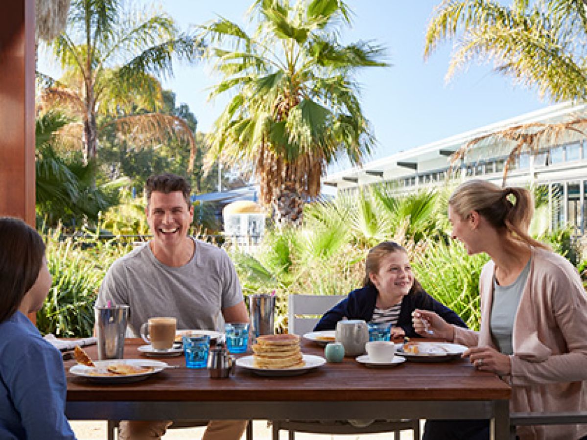 Family eating at outdoor table at poolside cafe at RACV Cobram Resort.