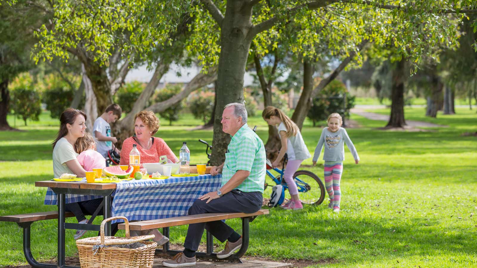 Family having a picnic and children playing at RACV Cobram Resort grounds.