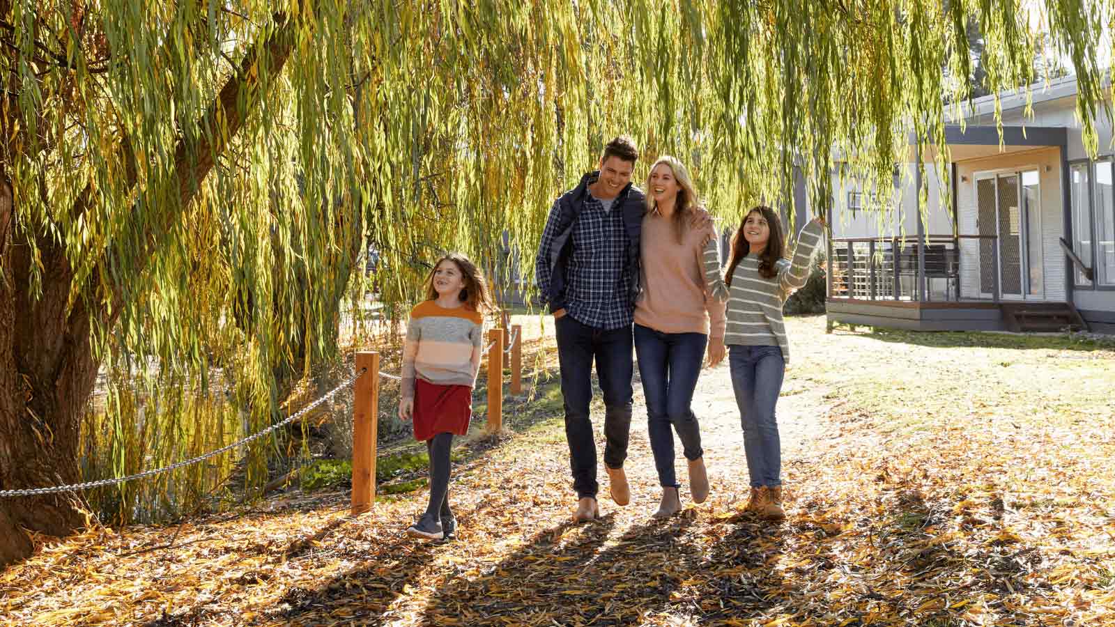 A young family walking under the riverside trees along the Murray River.
