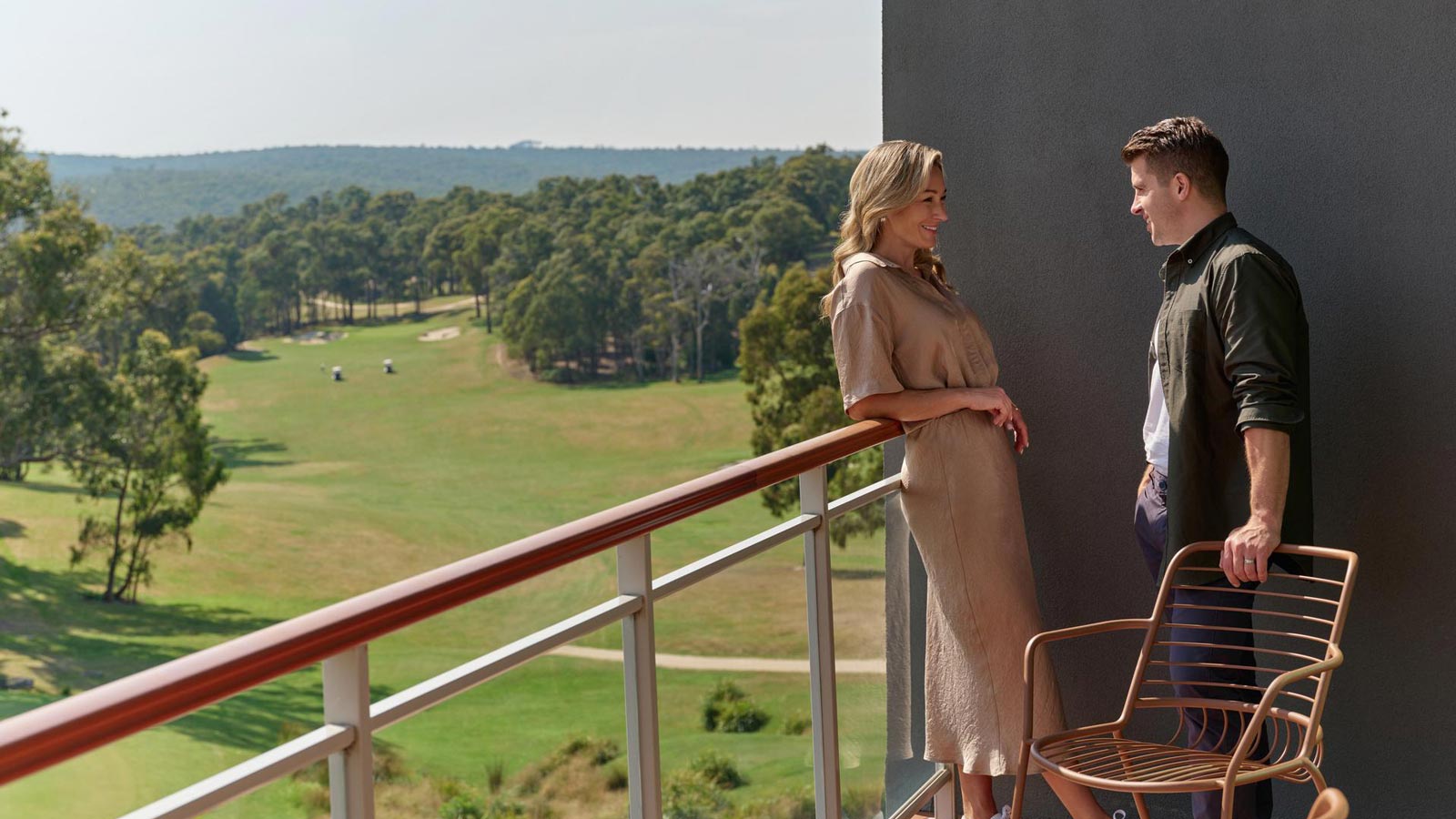 Man and woman standing on the balcony overlooking the golf course