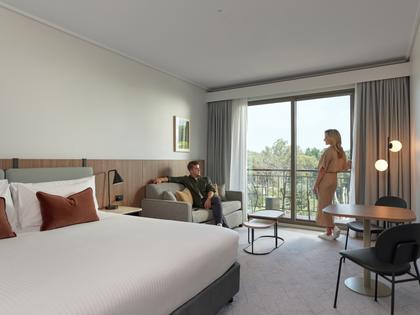 A couple relaxing in the RACV Goldfields room that overlooks lush green views.
