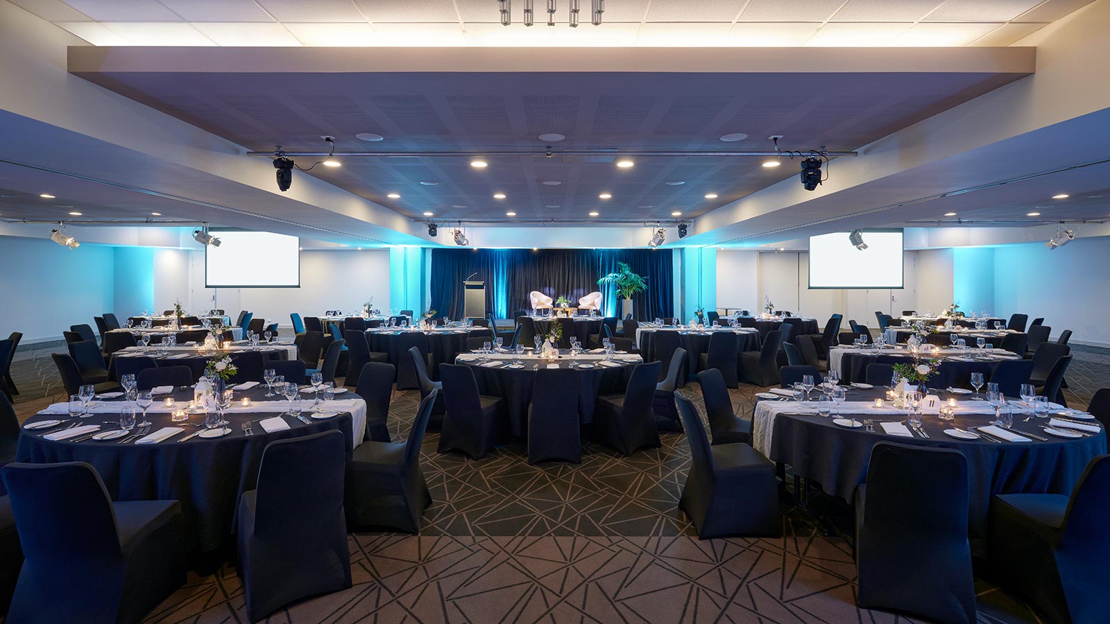 Grand Ballroom at RACV Goldfields Resort, set up banquet style with screens coming down from the ceiling.