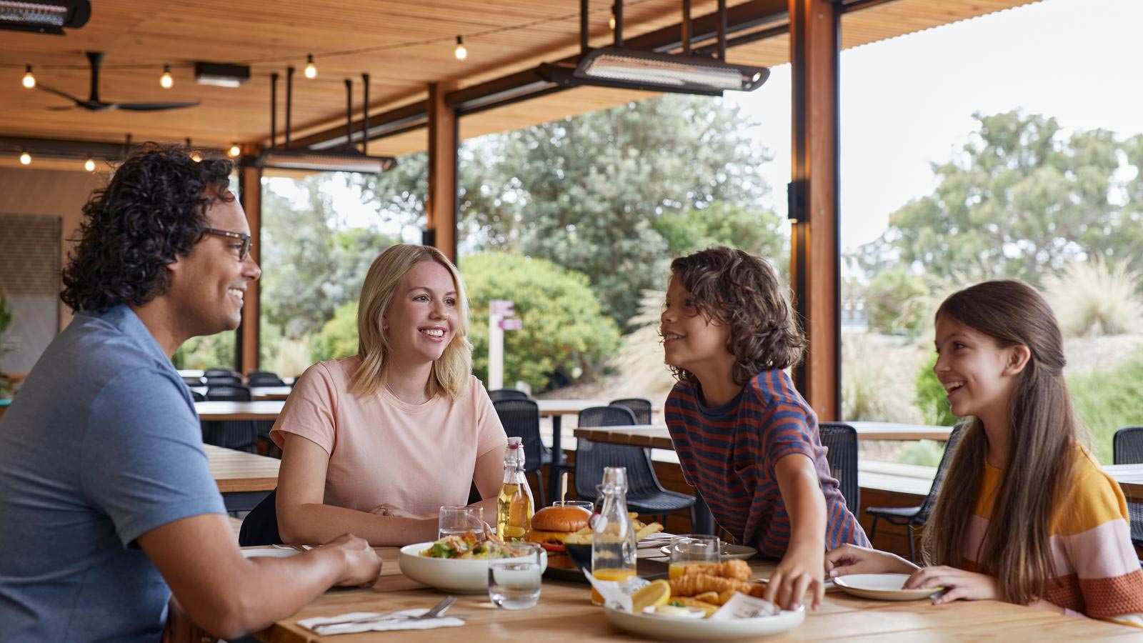Family sharing a meal in the outdoor seating of Three Founders Beer Garden at RACV Goldfields Resort.