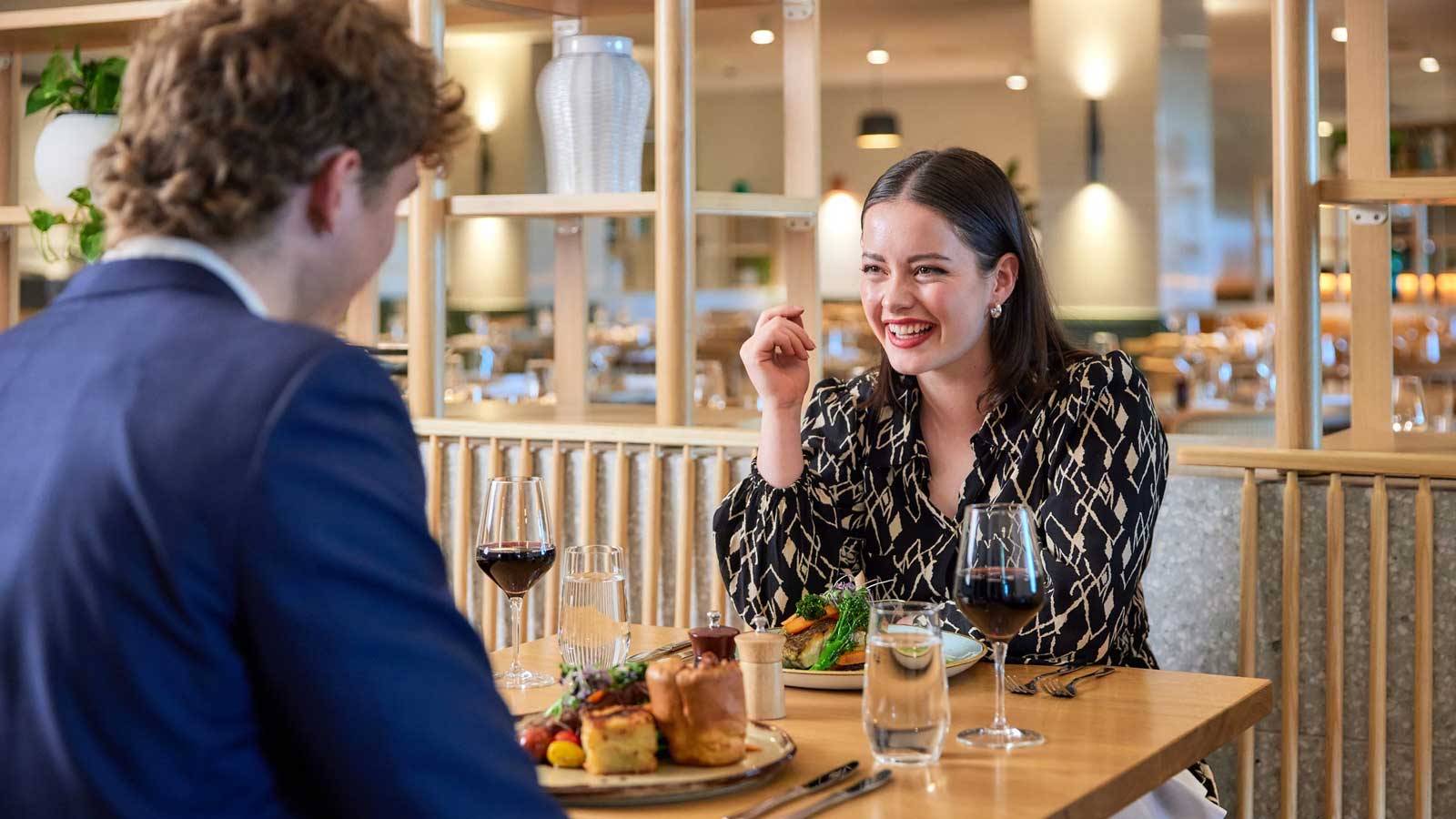 A young couple enjoying dinner and some wine at Three Founders restaurant. 