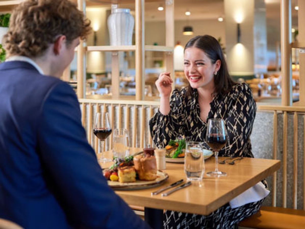 A young couple enjoying dinner and some wine at Three Founders restaurant. 