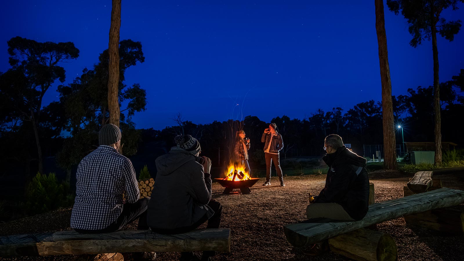 People standing at sitting around a campfire at RACV Goldfields Resort.