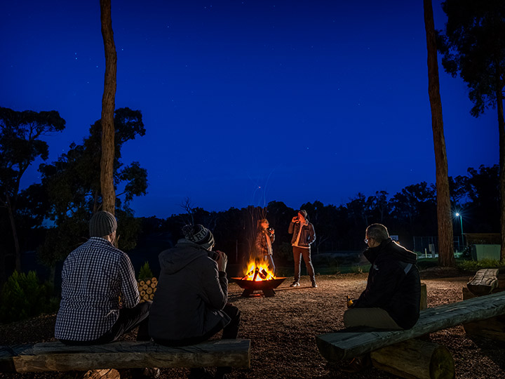 People standing at sitting around a campfire at RACV Goldfields Resort.