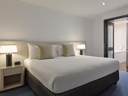 Bed with night stands in deluxe apartment with harbour views at RACV Hobart Resort.