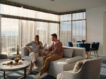 A couple enjoying a drink on the lounge of their penthouse room at the RACV Hobart Hotel.