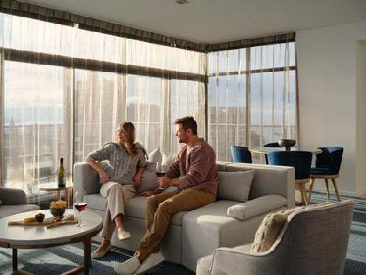 A couple enjoying a drink on the lounge of their penthouse room at the RACV Hobart Hotel.