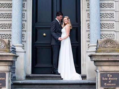 Bride and groom posing in front of the Law Society of Tasmania building.