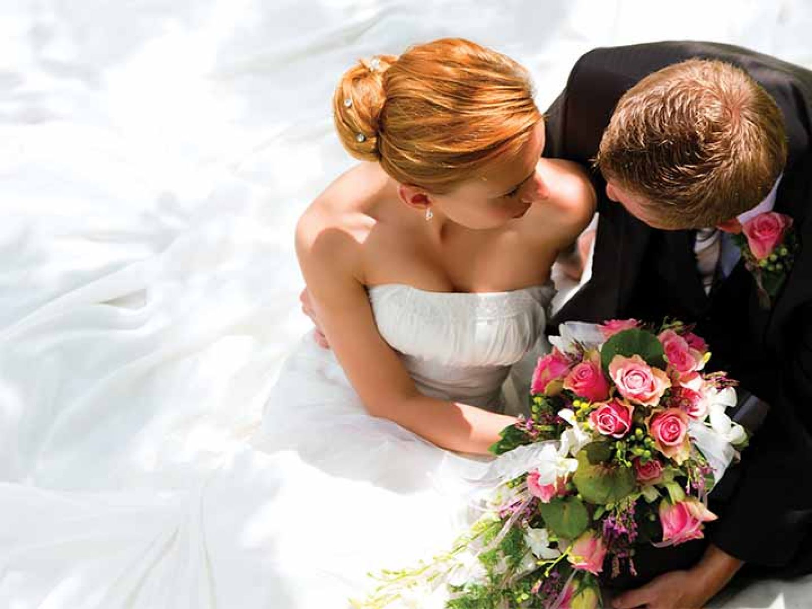 A Bride and groom looking at each other while sitting down.