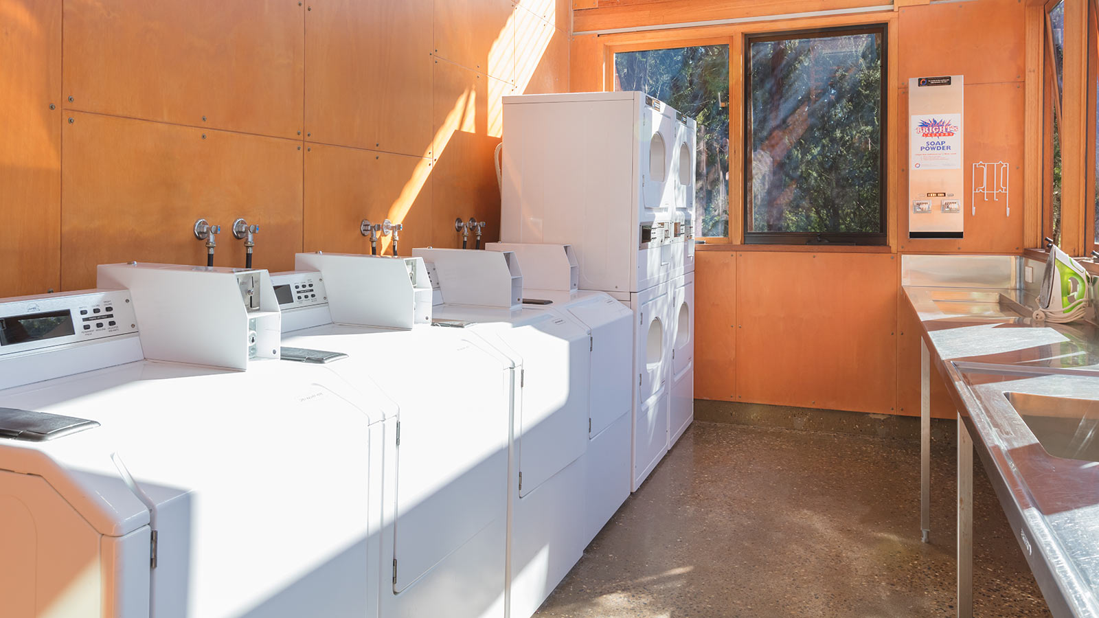 Shared laundry facilities at RACV Inverloch Resort's caravan site, featuring a sink, iron and washers and dryers.