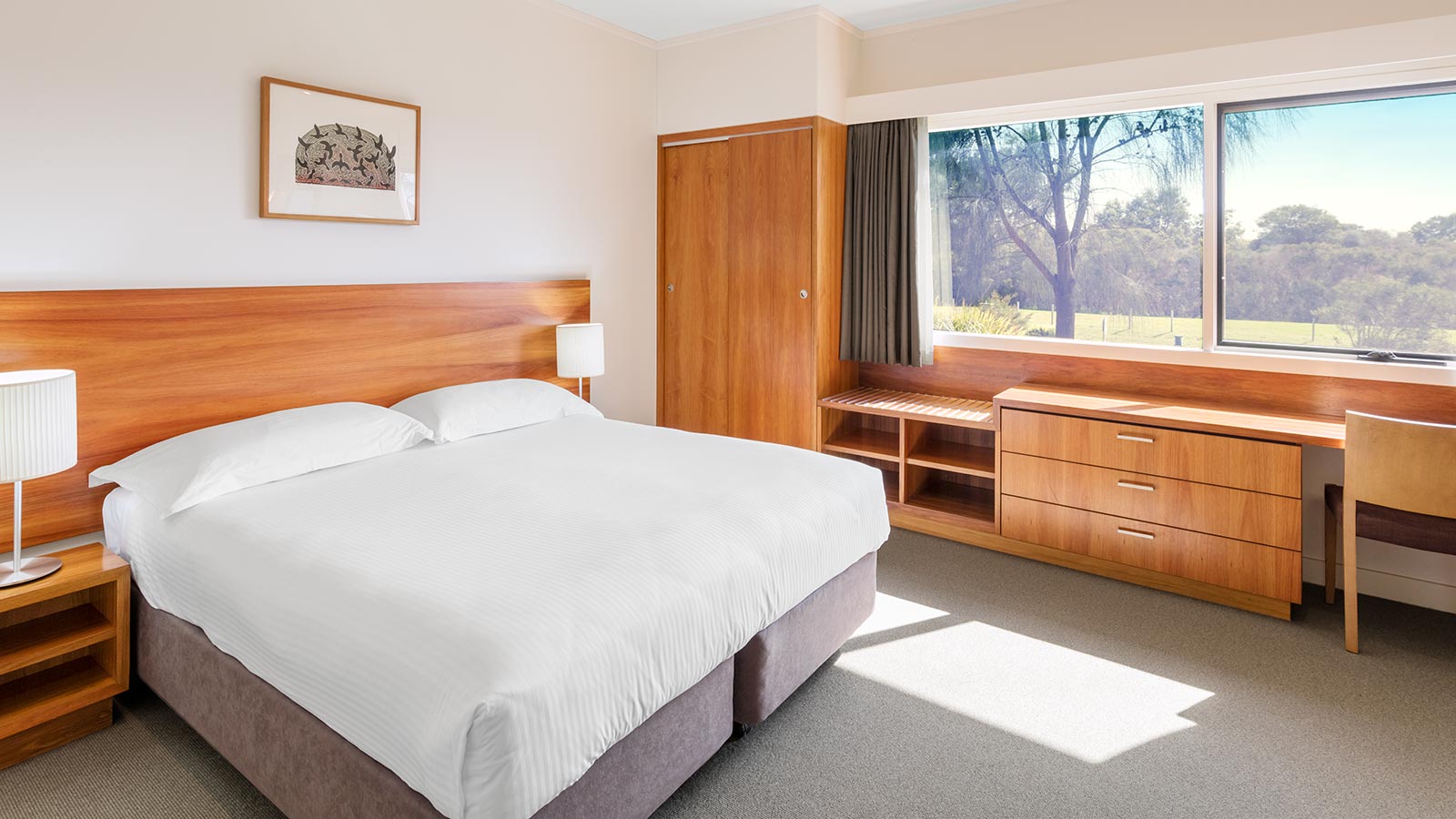 Premium villa at RACV Inverloch Resort, featuring a large bed, wooden cabinets and desk.