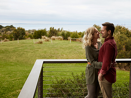 Couple hugging on a balcony overlooking the ocean at RACV Inverloch Resort.