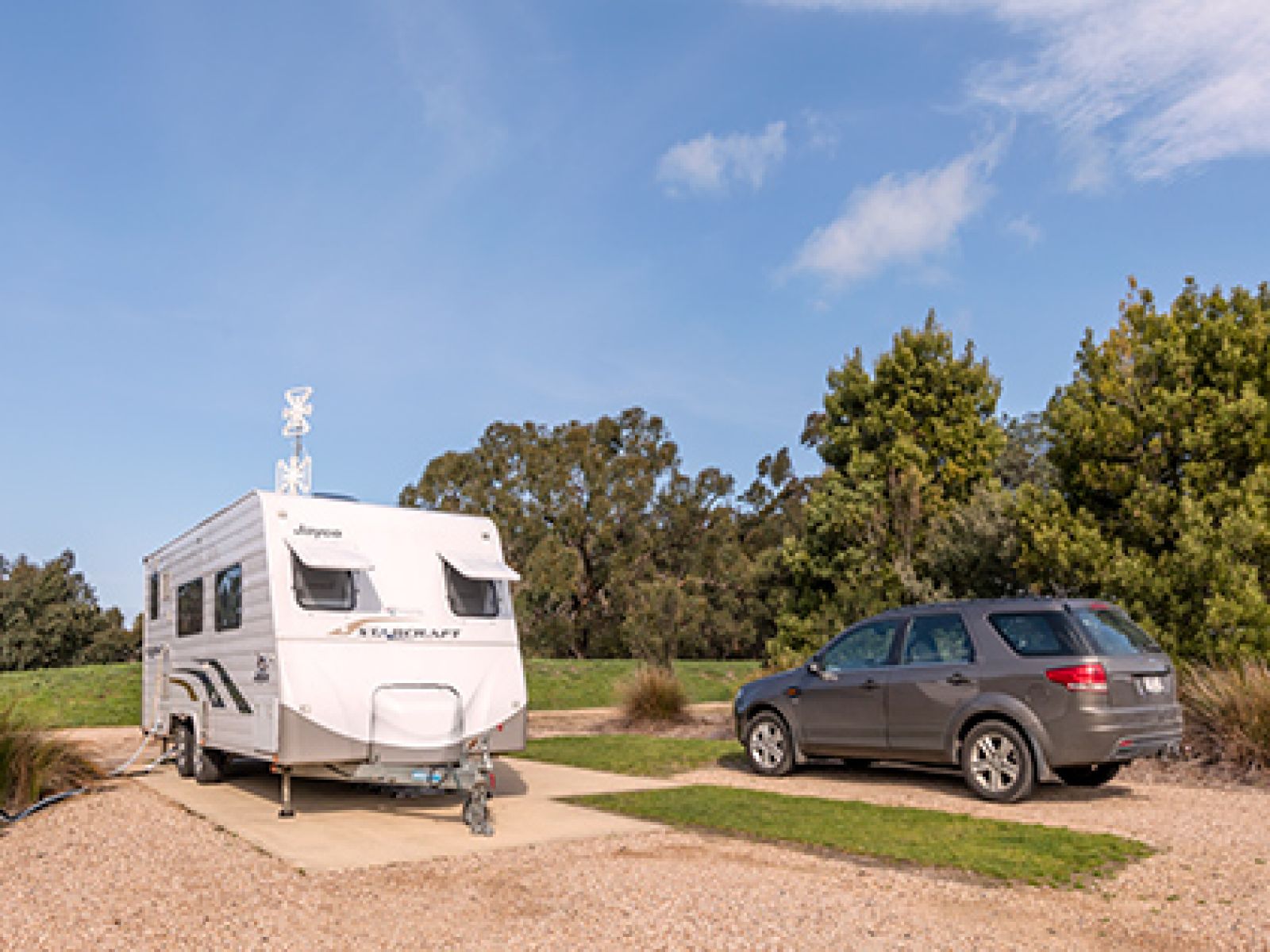 White caravan parked next to brown SUV in front of field at RACV Inverloch Resort.
